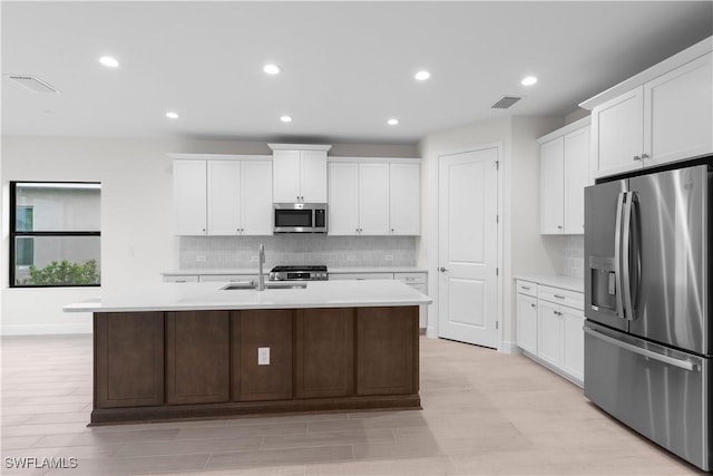 13617 Heritage Preserve Dr, Fort Myers, FL 33905 - kitchen featuring appliances with stainless steel finishes, backsplash, light countertops, an island with sink, and light wood-style flooring