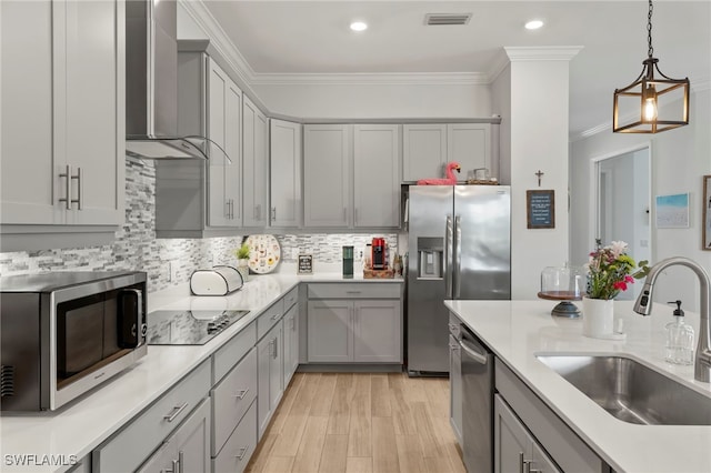 kitchen featuring crown molding, wall chimney range hood, sink, and appliances with stainless steel finishes