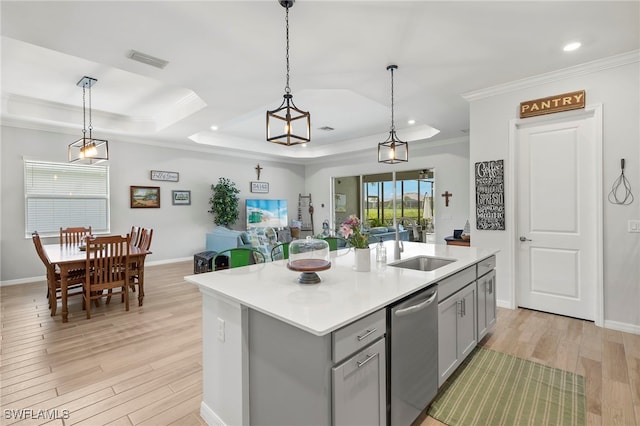 kitchen featuring dishwasher, a raised ceiling, an island with sink, decorative light fixtures, and gray cabinets