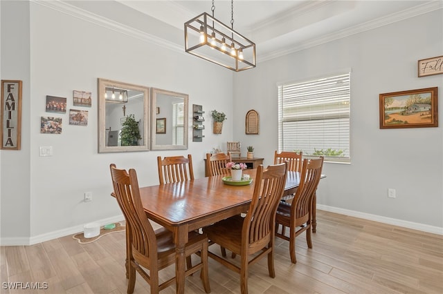 dining space featuring a notable chandelier, light wood-type flooring, crown molding, and a tray ceiling