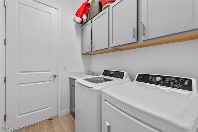 laundry room featuring light hardwood / wood-style floors, cabinets, separate washer and dryer, and sink