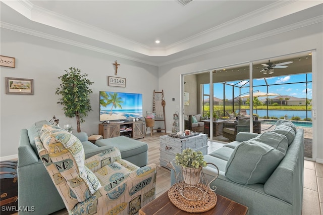 living room with ceiling fan, a raised ceiling, light wood-type flooring, and crown molding