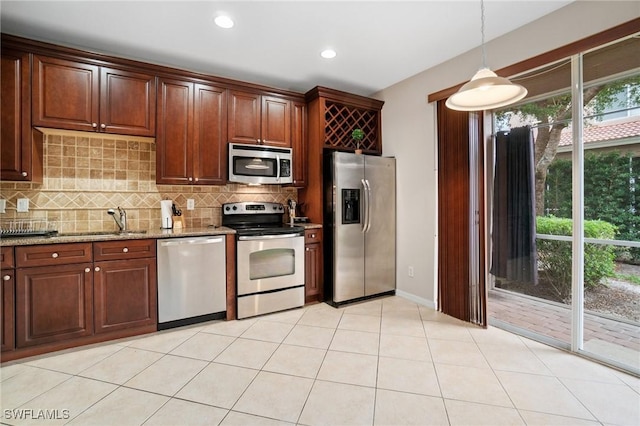 kitchen with sink, hanging light fixtures, decorative backsplash, appliances with stainless steel finishes, and light stone counters