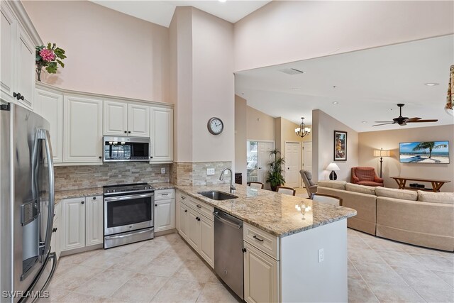 kitchen featuring appliances with stainless steel finishes, kitchen peninsula, light stone countertops, sink, and white cabinetry