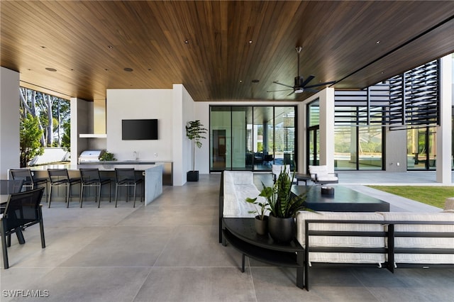 view of patio / terrace featuring a ceiling fan, a sink, outdoor wet bar, a grill, and an outdoor kitchen