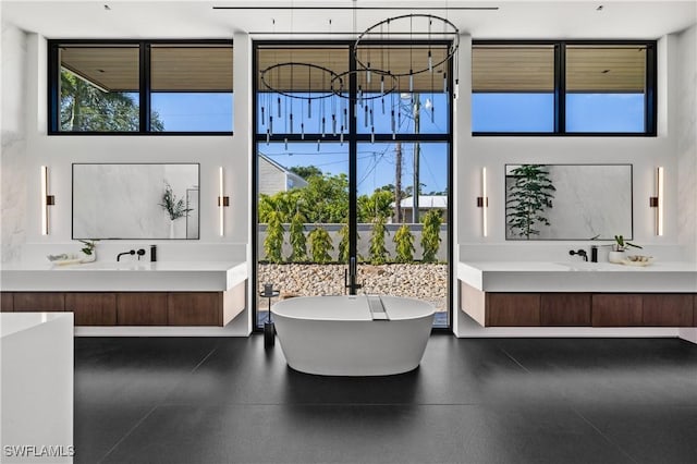 bathroom with vanity, a notable chandelier, floor to ceiling windows, and a soaking tub