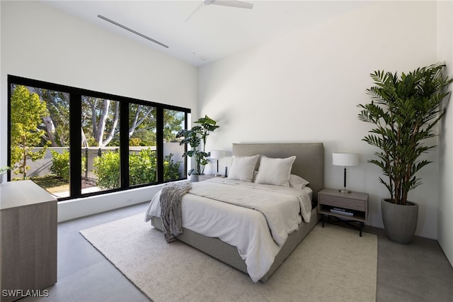 bedroom with ceiling fan, multiple windows, and finished concrete floors