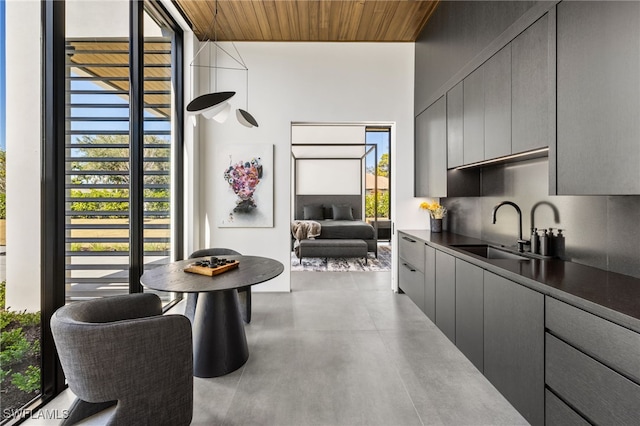 kitchen with finished concrete floors, dark countertops, gray cabinetry, and a sink