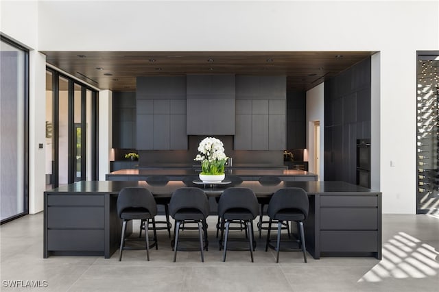 kitchen with dark countertops, a kitchen island, a breakfast bar, modern cabinets, and dobule oven black