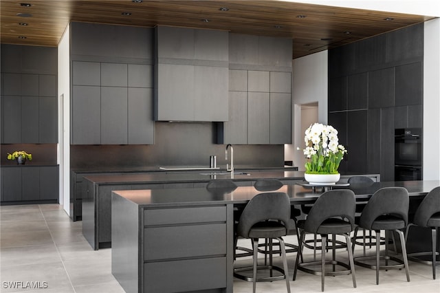 kitchen featuring wood ceiling, a center island with sink, and modern cabinets