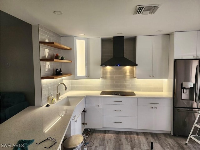 kitchen featuring white cabinets, stainless steel fridge with ice dispenser, black electric cooktop, and wall chimney exhaust hood