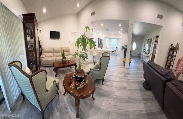 living room featuring high vaulted ceiling, visible vents, and wood finished floors