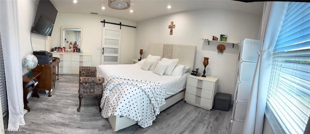 bedroom with a barn door, visible vents, wood finished floors, and recessed lighting