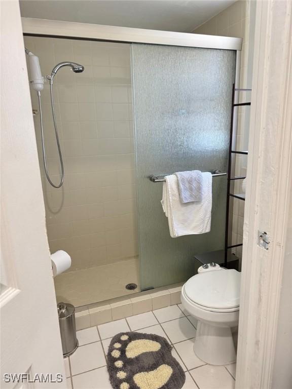 full bath with toilet, a shower stall, and tile patterned floors