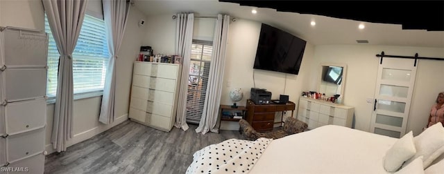 bedroom with baseboards, a barn door, wood finished floors, and recessed lighting