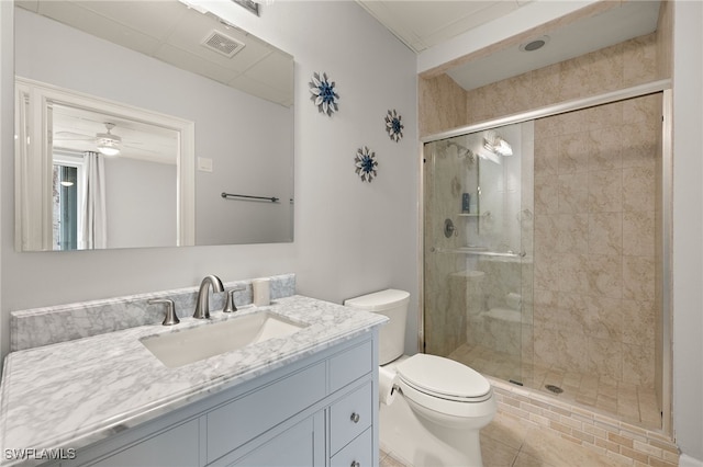 bathroom featuring tile patterned floors, toilet, vanity, a shower with door, and ceiling fan