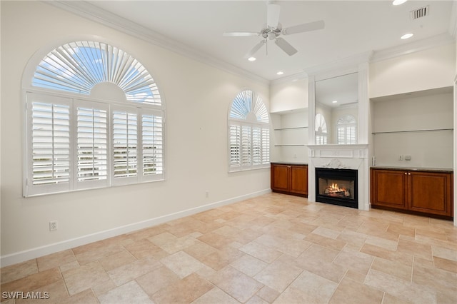 unfurnished living room with ceiling fan, built in features, crown molding, and a premium fireplace