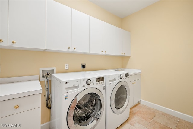 clothes washing area with light tile patterned flooring, cabinets, and washer and clothes dryer