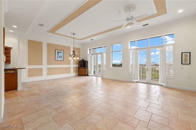 empty room with plenty of natural light, a tray ceiling, and ceiling fan with notable chandelier