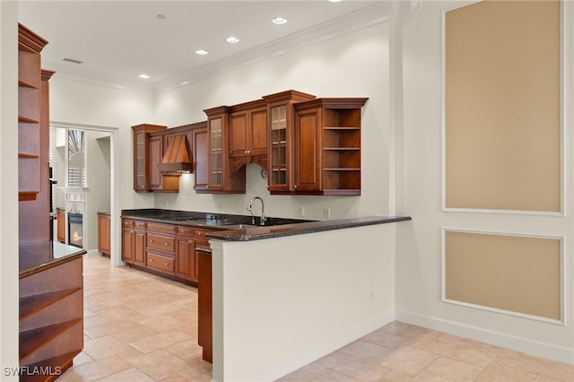 kitchen featuring wall chimney exhaust hood, sink, ornamental molding, kitchen peninsula, and dark stone counters