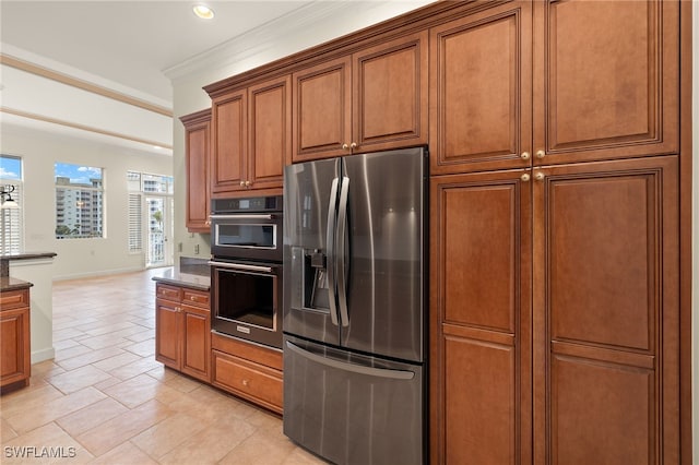 kitchen featuring double oven, stainless steel fridge, ornamental molding, and dark stone counters