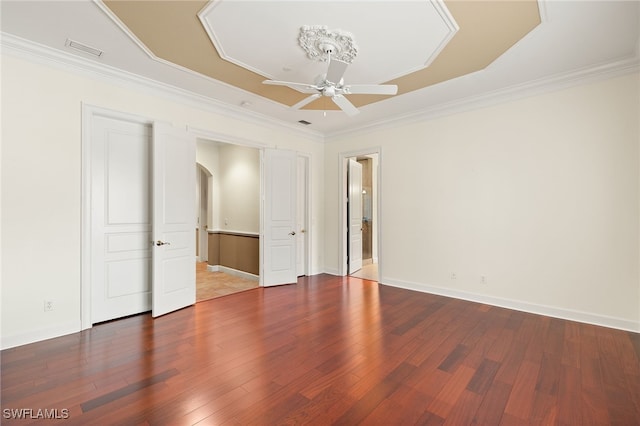 unfurnished bedroom featuring ornamental molding, a raised ceiling, and hardwood / wood-style floors