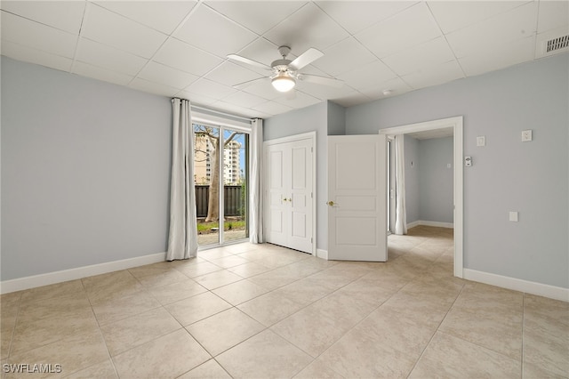 tiled empty room featuring a drop ceiling and ceiling fan