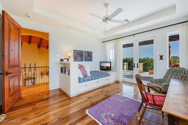 living area with a raised ceiling, light hardwood / wood-style flooring, and french doors