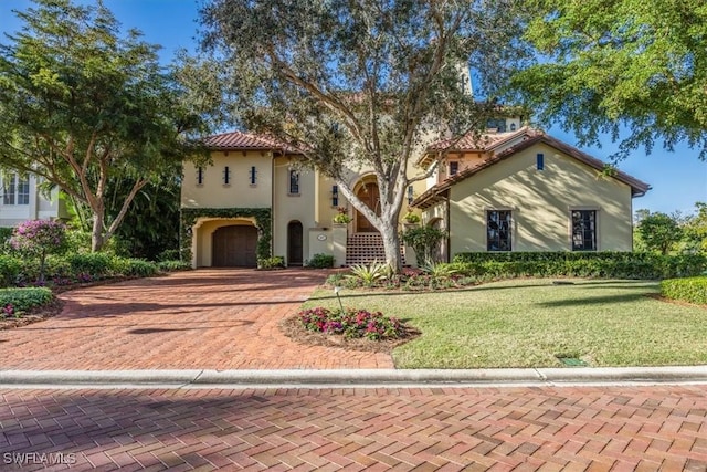 mediterranean / spanish house with a tiled roof, a front lawn, and stucco siding