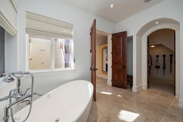 full bathroom featuring a freestanding tub and baseboards