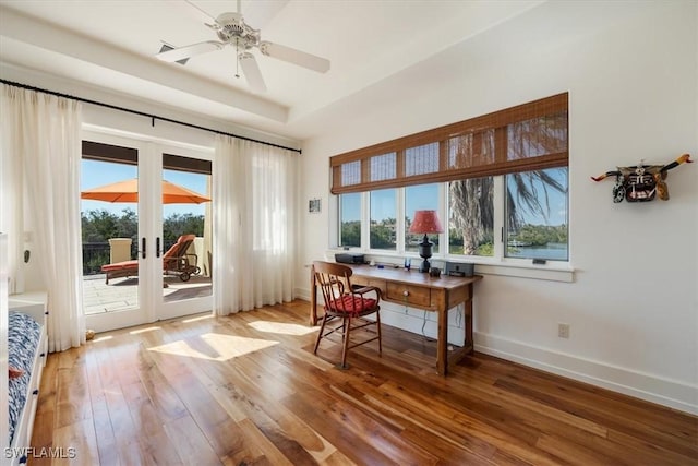 office with french doors, a raised ceiling, a ceiling fan, light wood-type flooring, and baseboards