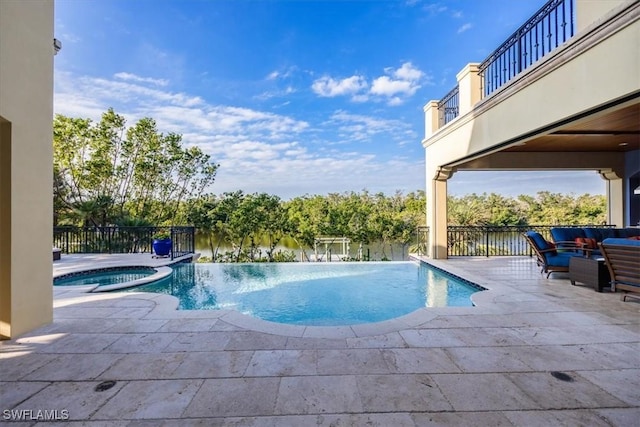 view of pool with a patio, fence, and a pool with connected hot tub