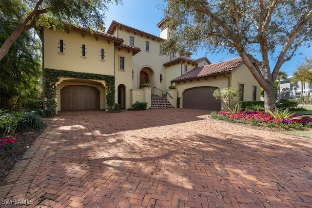 mediterranean / spanish-style home with a tile roof, decorative driveway, and stucco siding