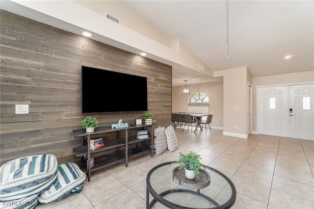 tiled living room featuring wooden walls, a chandelier, and lofted ceiling