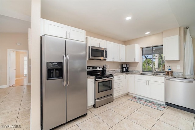 kitchen with light stone countertops, white cabinetry, light tile patterned flooring, and stainless steel appliances