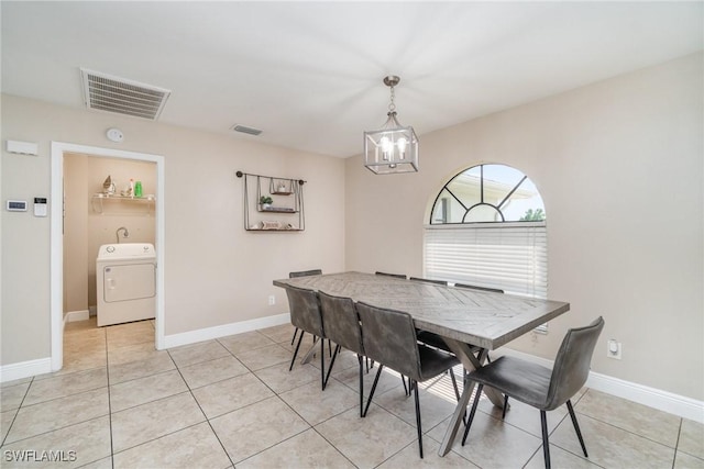 dining area with washer / dryer, an inviting chandelier, and light tile patterned floors