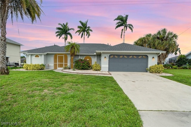 ranch-style home with a garage and a yard