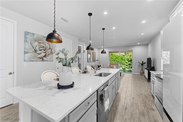 kitchen with pendant lighting, white cabinetry, sink, stainless steel appliances, and a spacious island