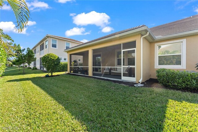 rear view of property with a sunroom and a yard