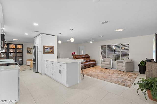 kitchen with stainless steel appliances, white cabinets, ceiling fan, and decorative light fixtures