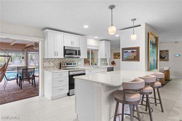 kitchen with backsplash, stainless steel appliances, decorative light fixtures, and white cabinets