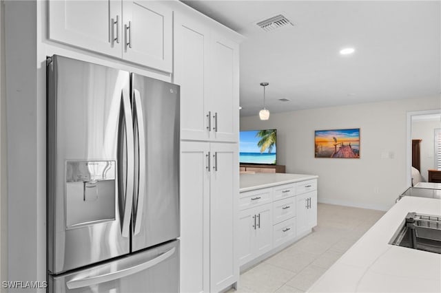 kitchen featuring white cabinets, hanging light fixtures, light tile patterned floors, stainless steel refrigerator with ice dispenser, and light stone countertops