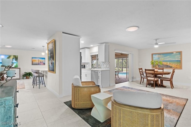 living room featuring light tile patterned flooring, ceiling fan, and sink