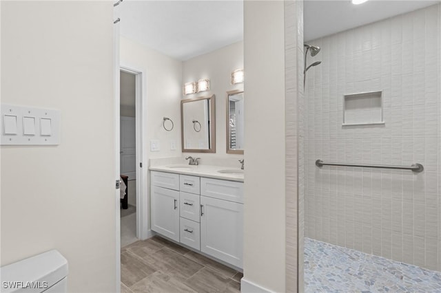 bathroom featuring vanity, tiled shower, and toilet