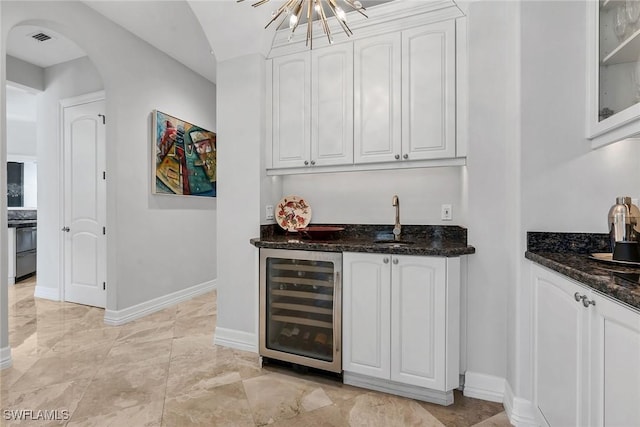 bar with dark stone counters, white cabinetry, and wine cooler