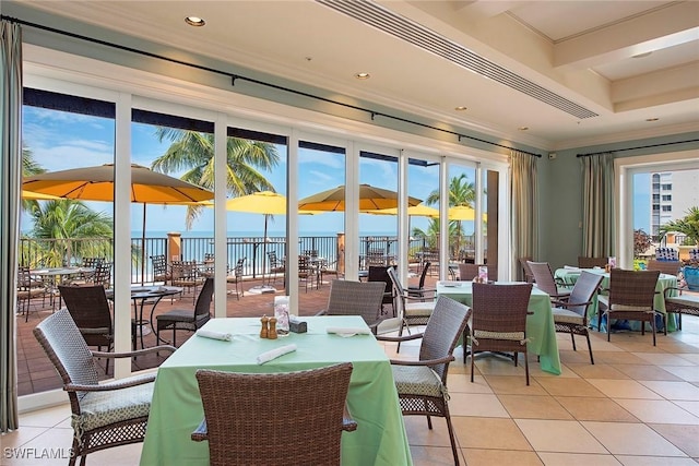 dining area featuring a water view, crown molding, and light tile patterned floors