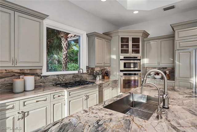 kitchen with sink, light stone countertops, appliances with stainless steel finishes, and decorative backsplash