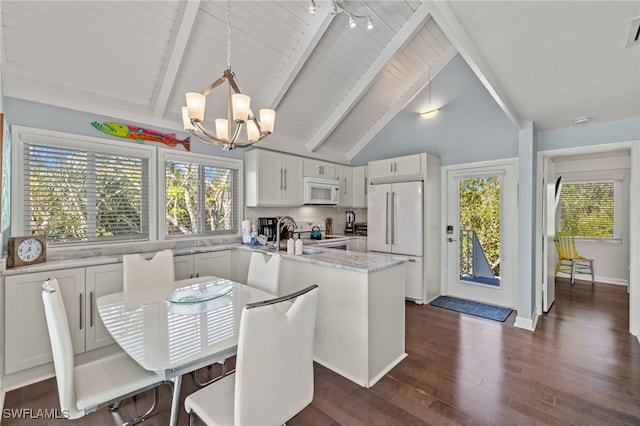 kitchen featuring white appliances, decorative light fixtures, a notable chandelier, white cabinets, and a center island