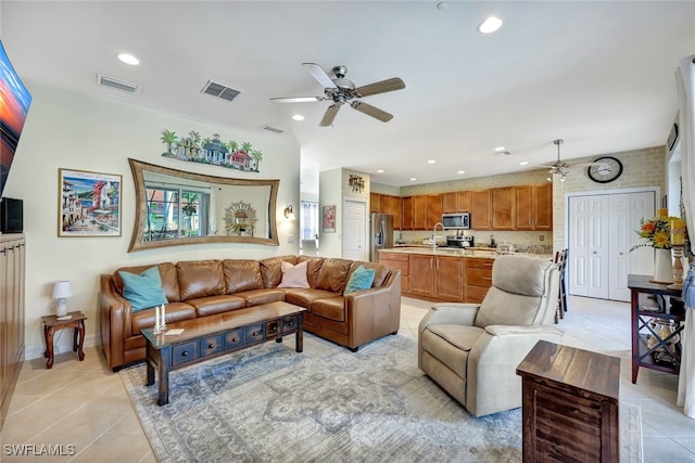 living room featuring ceiling fan, light tile patterned floors, sink, and brick wall