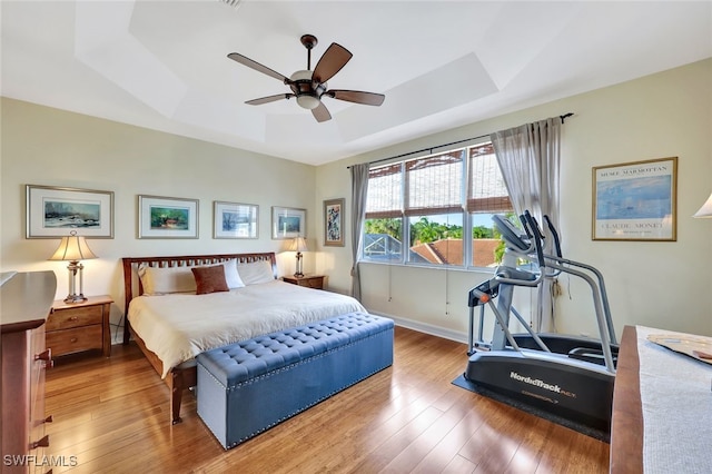 bedroom featuring ceiling fan, wood-type flooring, and a raised ceiling